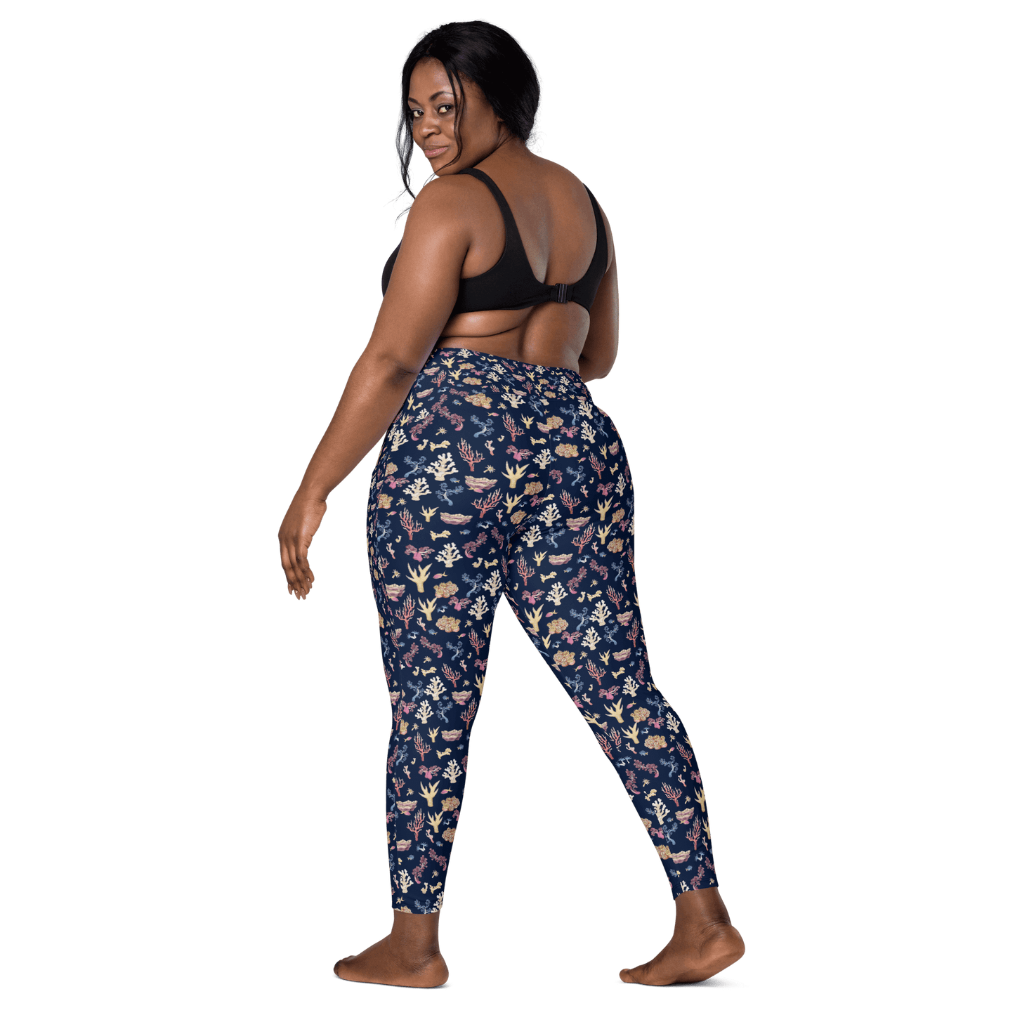 Woman wearing navy blue leggings with a colorful coral and sea life pattern