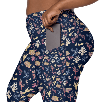 Woman wearing navy blue leggings with a colorful coral and sea life pattern and it has pockets