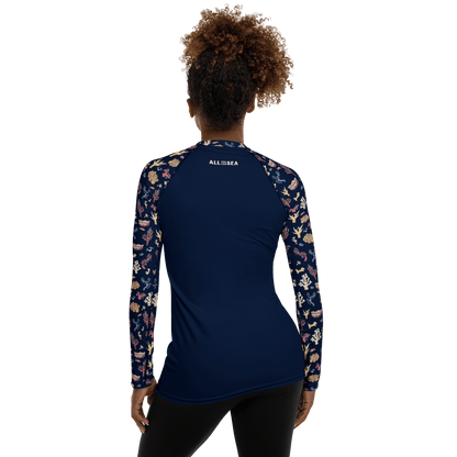Woman wearing All You Can Sea navy blue rashguard with a colorful coral and sea life pattern